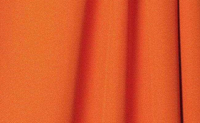 Tangerine-colored wrinkle-resistant fabric with smooth, seamless texture as a tangerine wrinkle-resistant background.